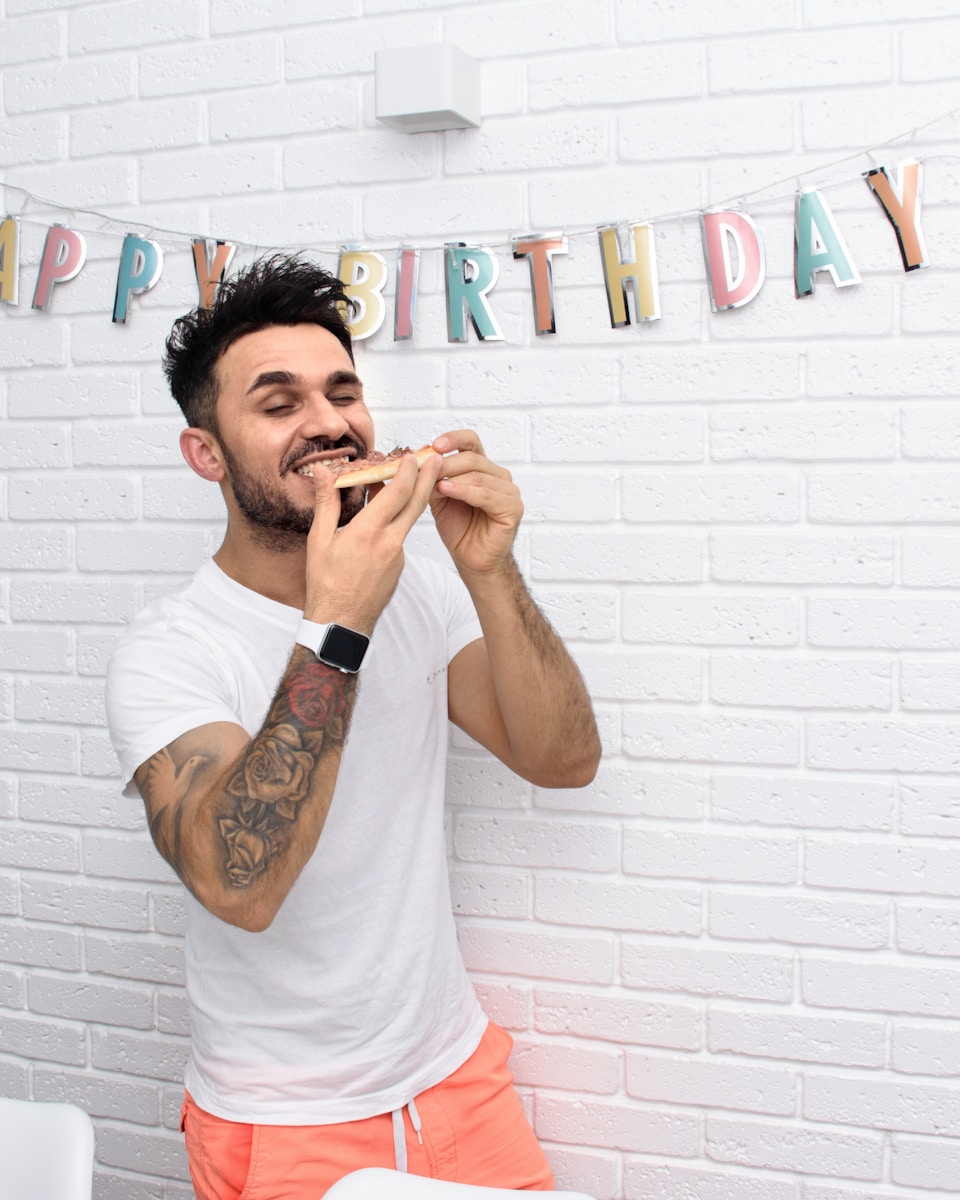 Man happily eats pizza on his birthday.